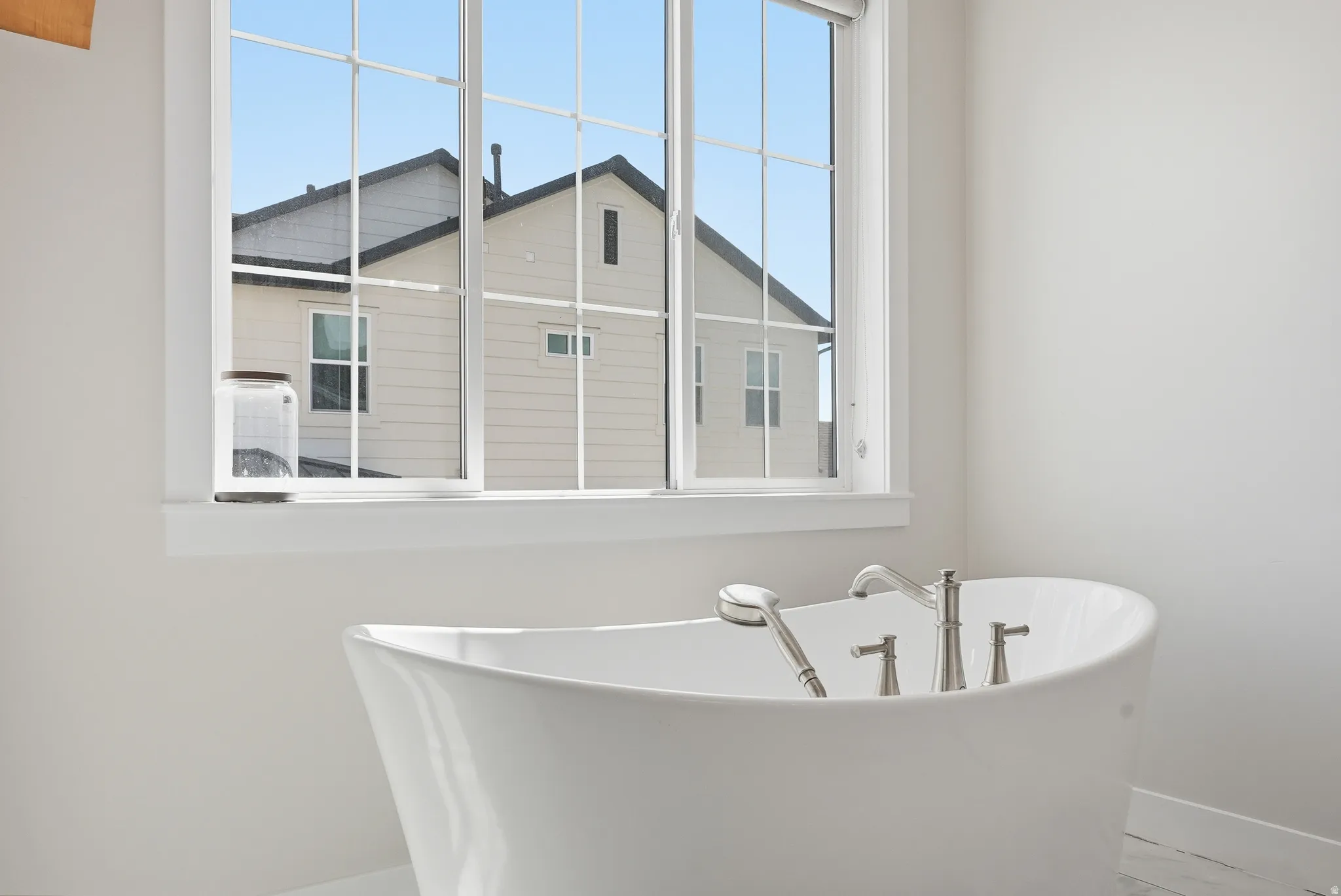 Freestanding soaking tub with brushed nickel fixtures and a handheld shower