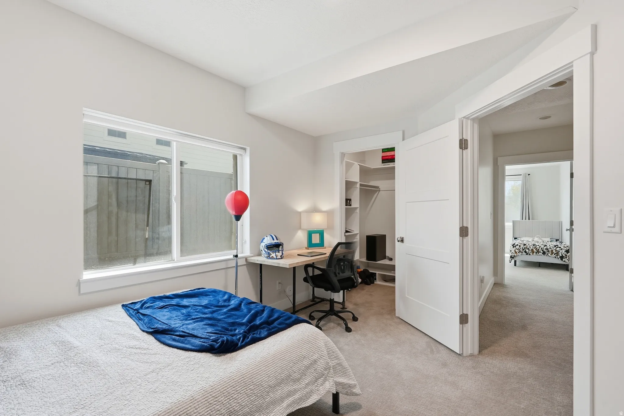 Carpeted bedroom featuring a sliding window, built-in closet shelving, and a modern paneled door