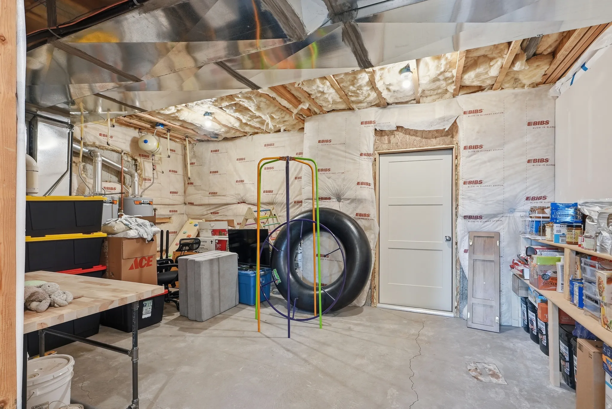 Unfinished basement space featuring exposed ceiling joists, ductwork, and insulated walls