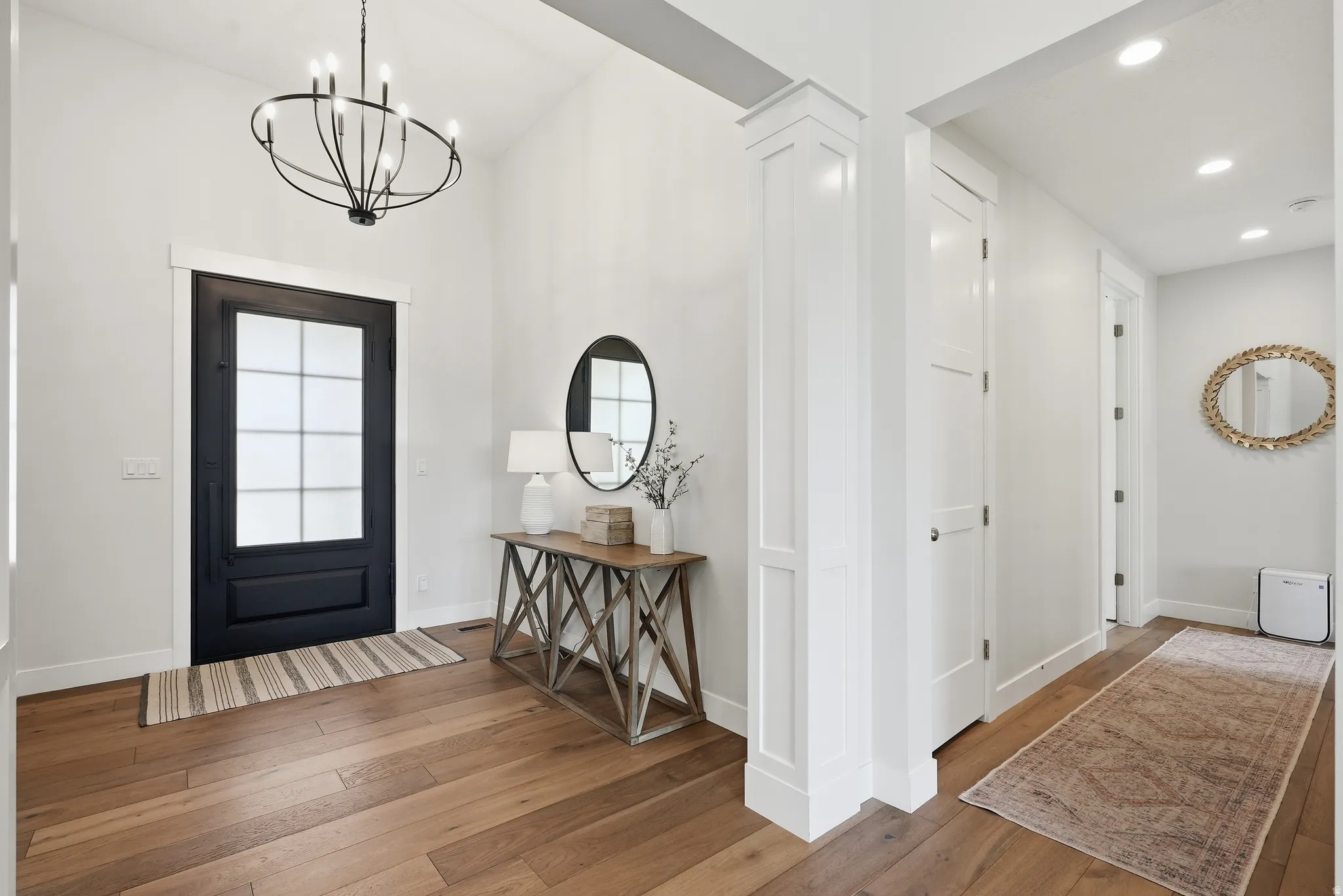 Entryway featuring a black paneled front door with divided lites, high ceilings, wood-finish flooring, and a contemporary chandelier