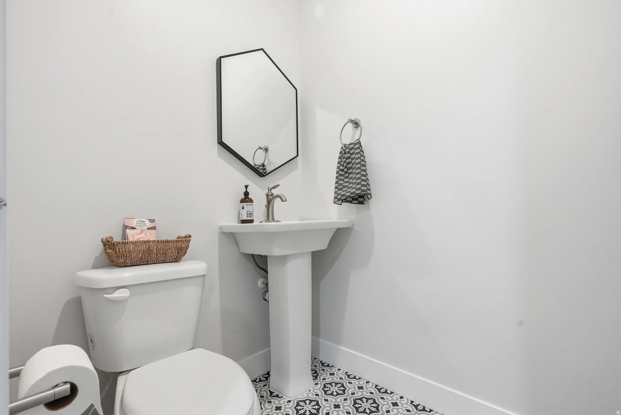 Pedestal sink with a geometric black-framed mirror