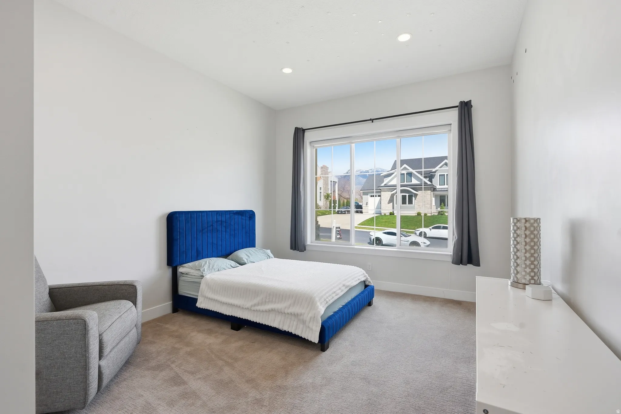 Bright interior space featuring a large window with white framing, recessed lighting, and neutral carpeting