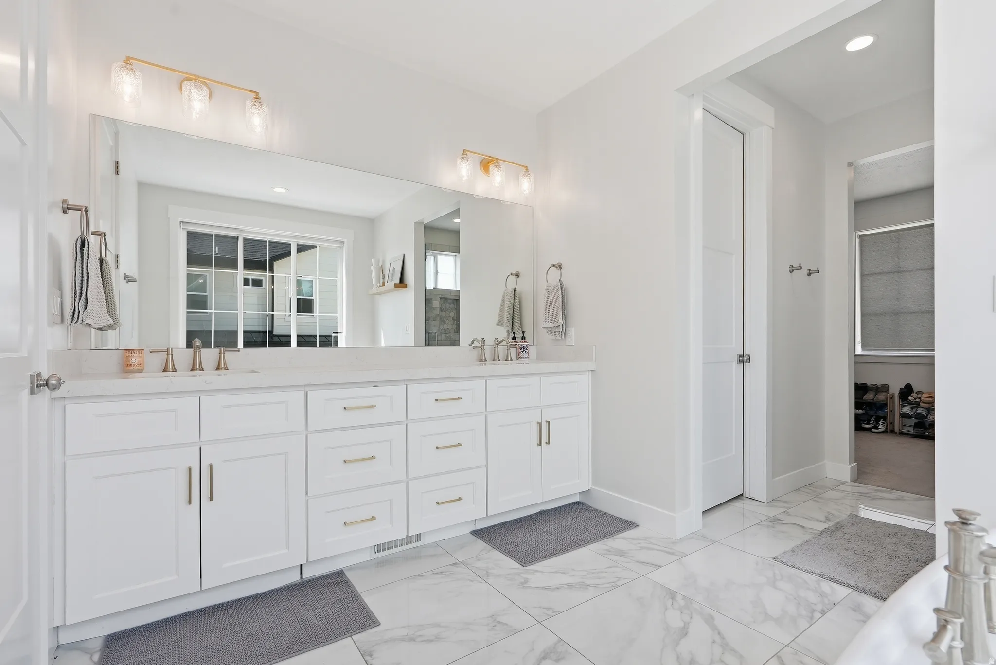 Double vanity featuring white cabinetry, a light-toned countertop, and dual sinks with rose gold-toned fixtures