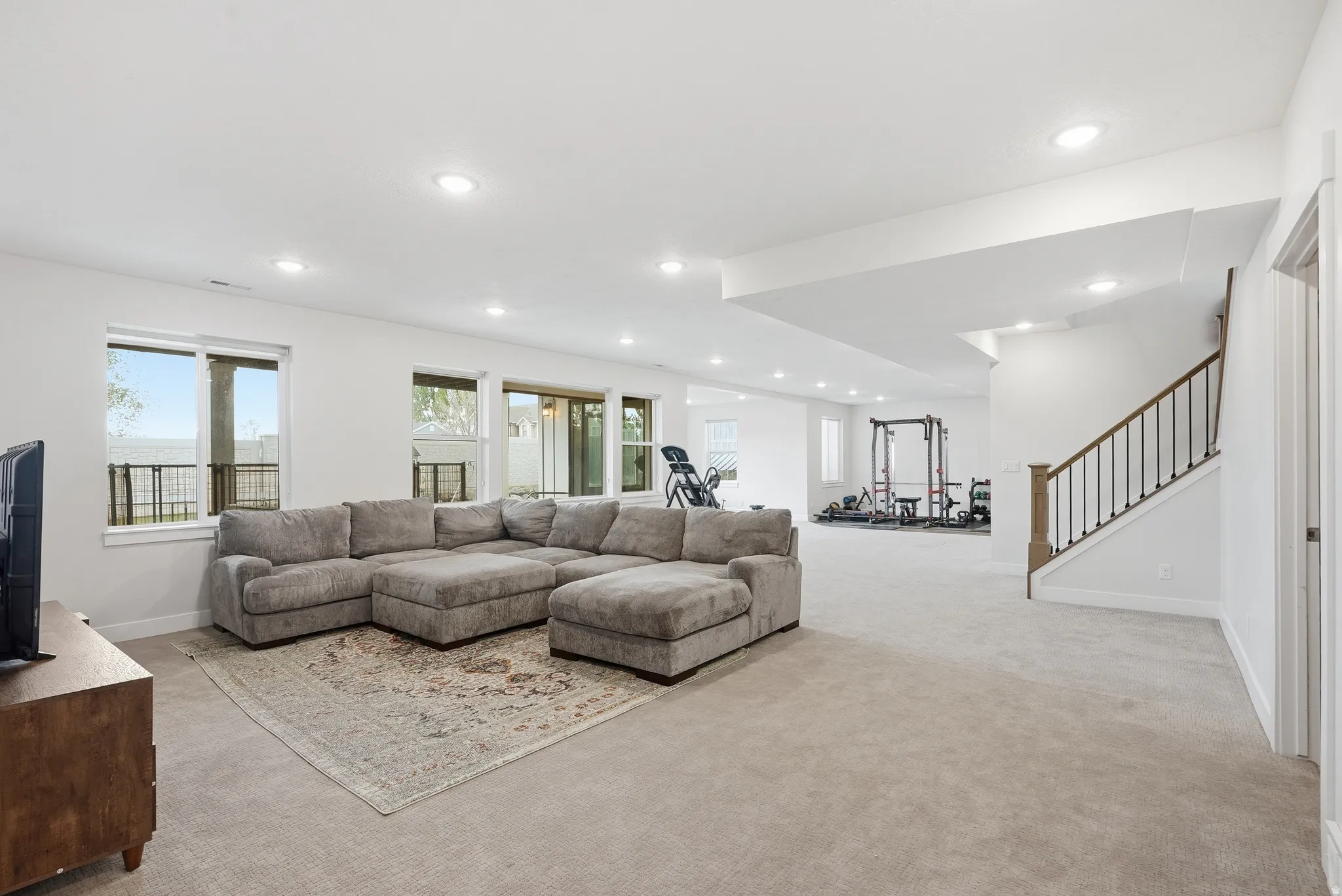 Spacious lower-level living area with recessed lighting and light-toned carpeting