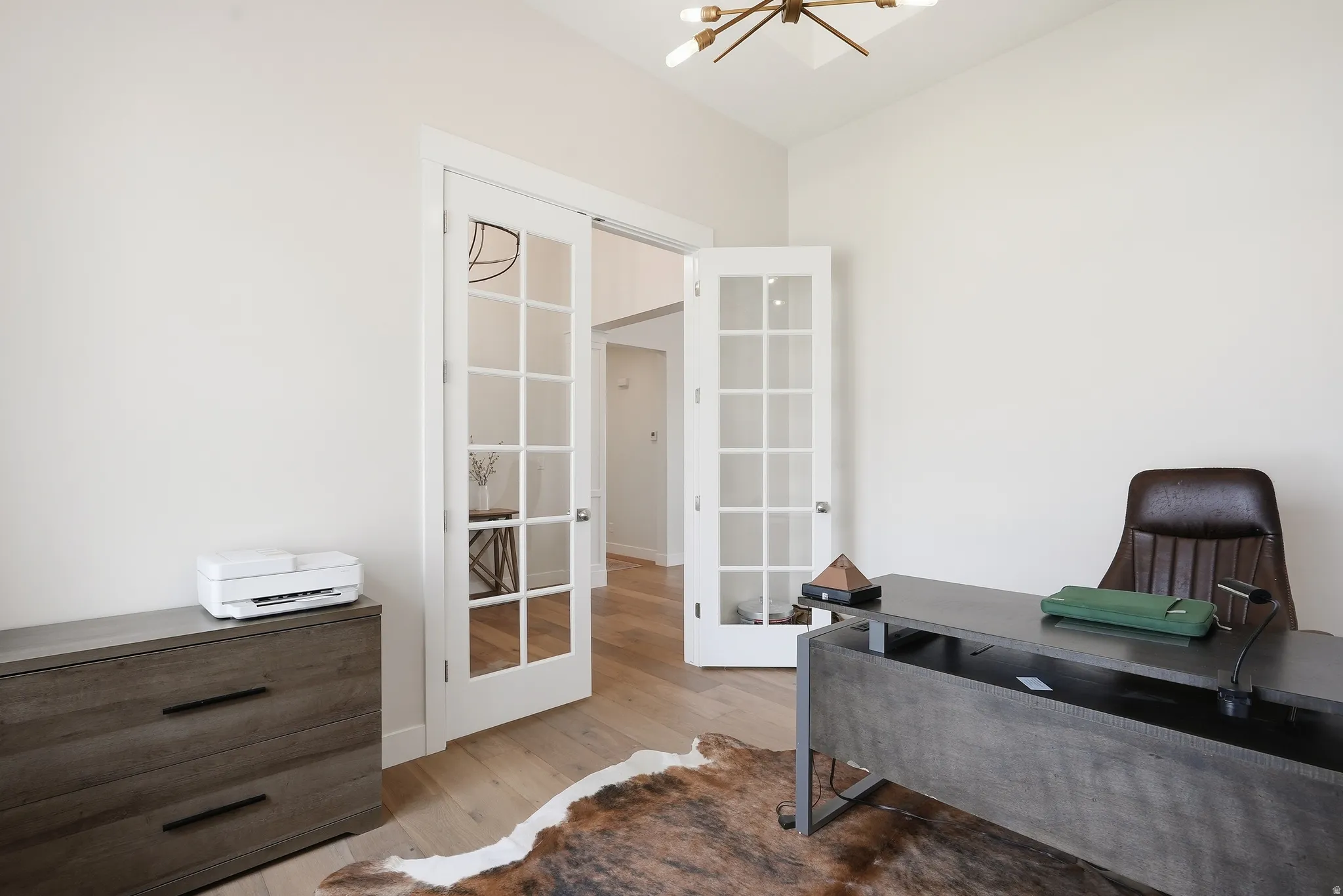 Room with French doors, wood-finish flooring, and a contemporary ceiling light fixture