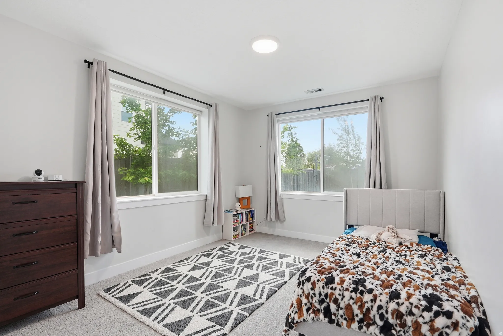 Light-filled room featuring two windows with white trim, gray walls, and gray carpet flooring