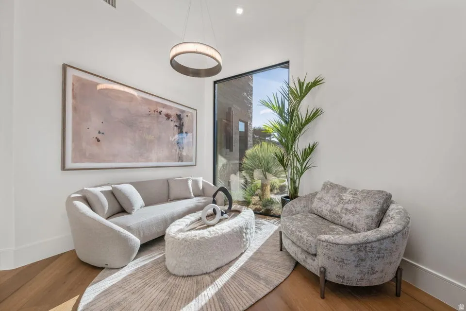 Bright interior space featuring a floor-to-ceiling window, wood-finish flooring, and a contemporary circular pendant light fixture