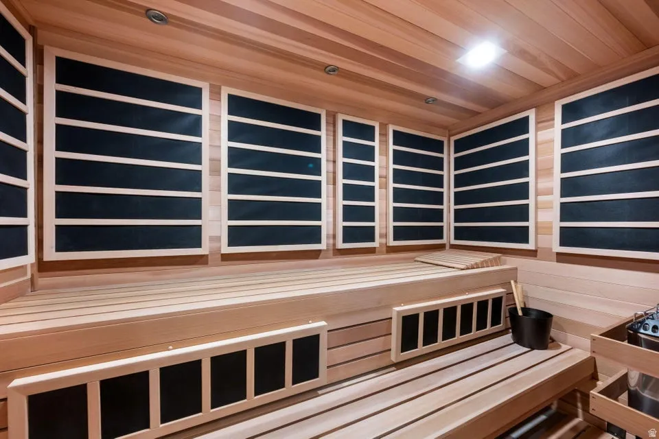 Custom sauna room featuring light wood paneling, built-in benches, recessed ceiling lighting, and multiple heating elements