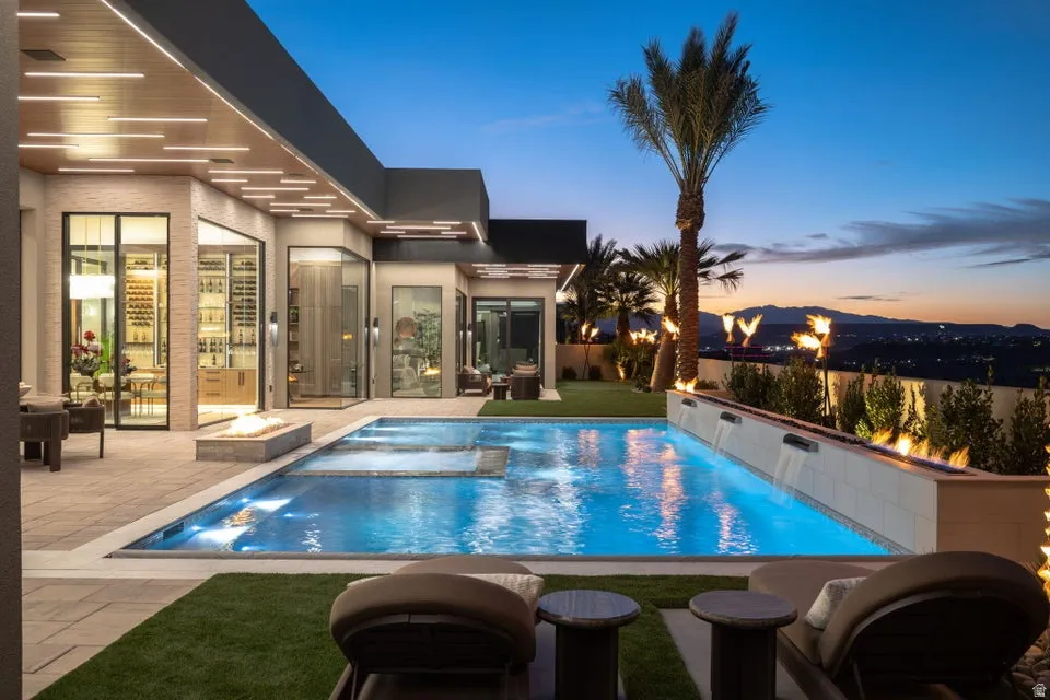 Contemporary outdoor pool with integrated spa, adjacent fire pit, and multiple water features
