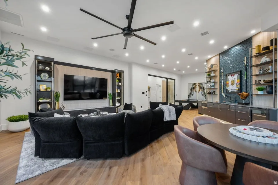 Expansive entertainment space featuring wood-finish flooring, a contemporary ceiling fan, and abundant recessed lighting