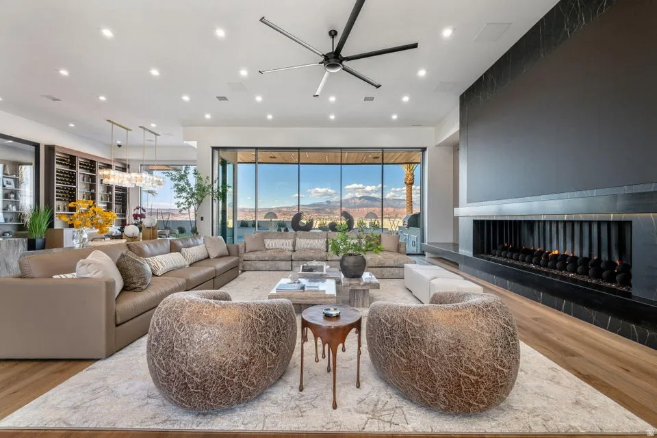 Expansive living area featuring wood-finish flooring, a linear fireplace with a black stone surround, and floor-to-ceiling windows