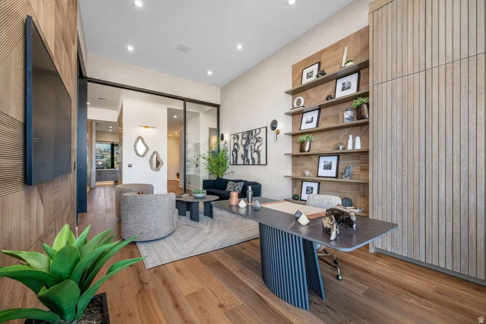 Spacious room featuring wood-finish flooring, a wood-paneled accent wall, and recessed lighting