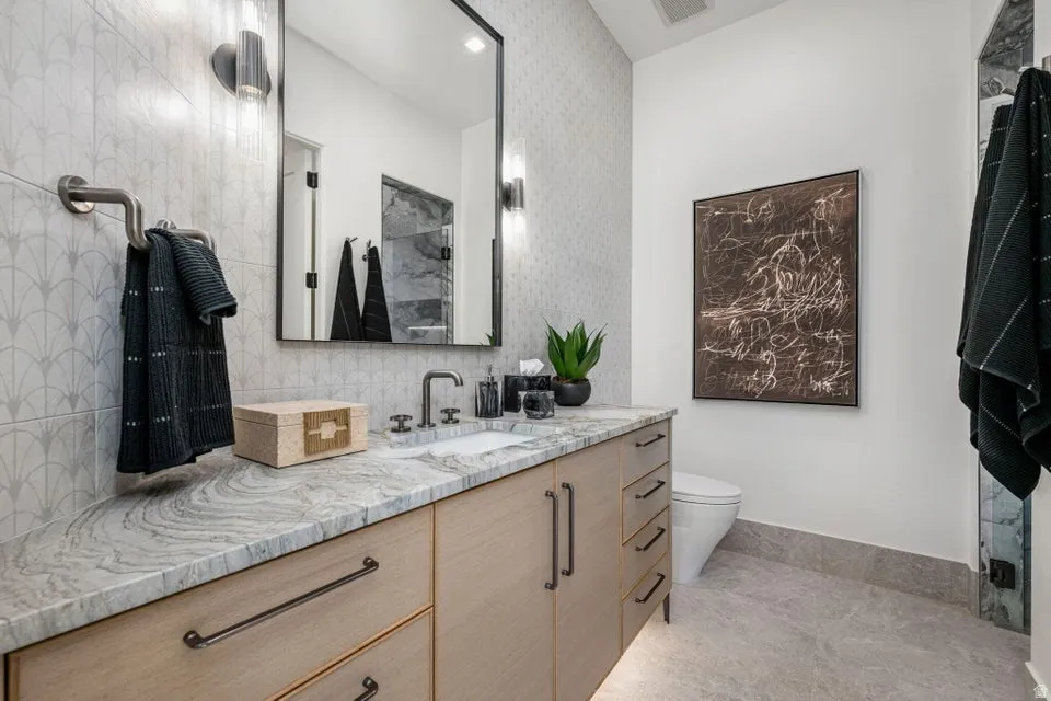 Contemporary vanity featuring light wood-finish cabinetry, a single integrated sink, and dark hardware