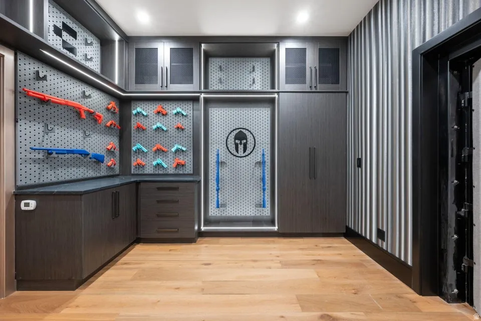 Custom storage room featuring wood-finish flooring and integrated cabinetry with varied storage options