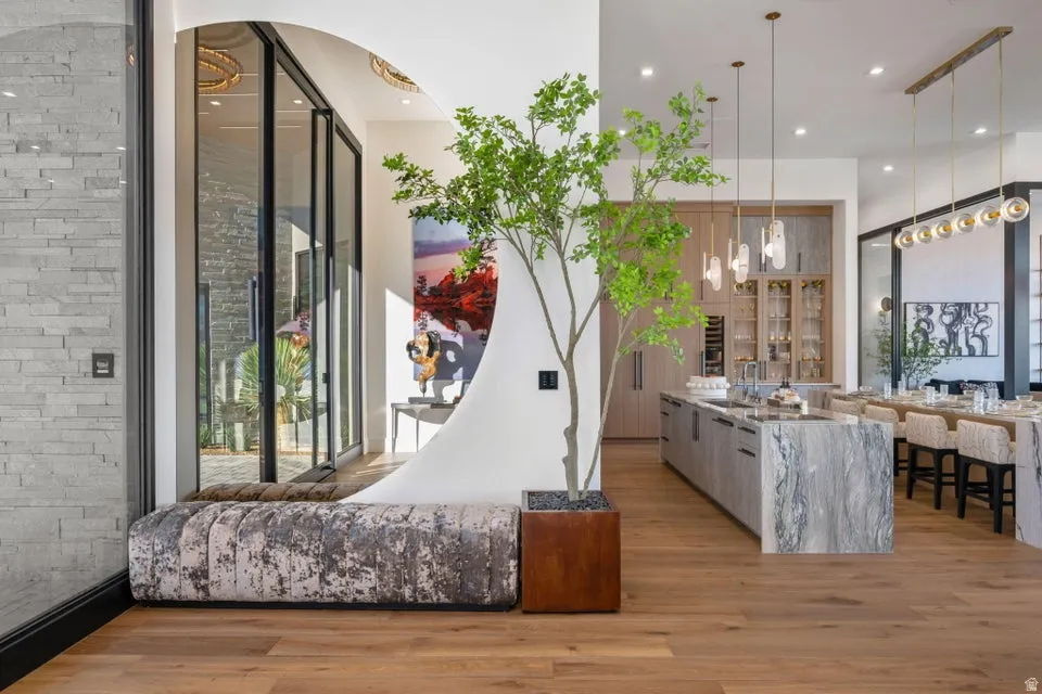 Open-concept living area featuring wide-plank wood-finish flooring, a large kitchen island with a stone finish, and built-in cabinetry with integrated appliances