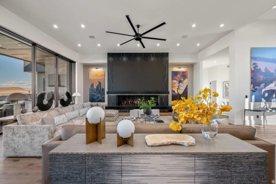 Open-concept living area featuring a sleek black fireplace, floor-to-ceiling sliding glass doors, recessed lighting, wood-finish flooring, and a modern ceiling fan