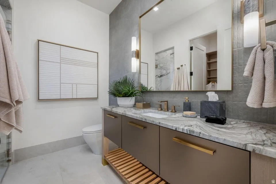 Bathroom vanity featuring a natural stone countertop with integrated sink, bronze-finish fixtures, and a large framed mirror