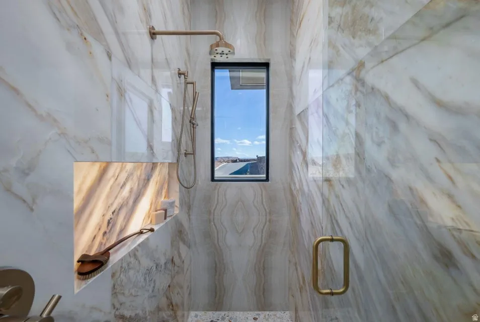 Walk-in shower with full-height stone-look tile walls, an integrated niche with backlighting, a fixed showerhead, and a handheld shower attachment