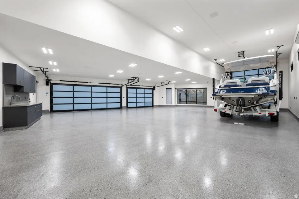 Spacious garage featuring two translucent panel garage doors, concrete flooring, recessed lighting, and built-in cabinetry with a sink