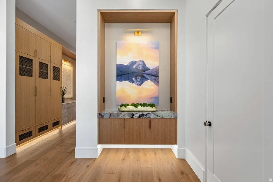 Built-in alcove with a polished stone countertop and wood-finish cabinetry, illuminated by integrated lighting and a wall-mounted fixture