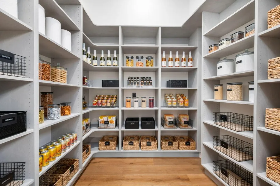 Custom-built pantry featuring extensive shelving, corner storage, adjustable shelf heights, integrated lighting, and wood-finish flooring