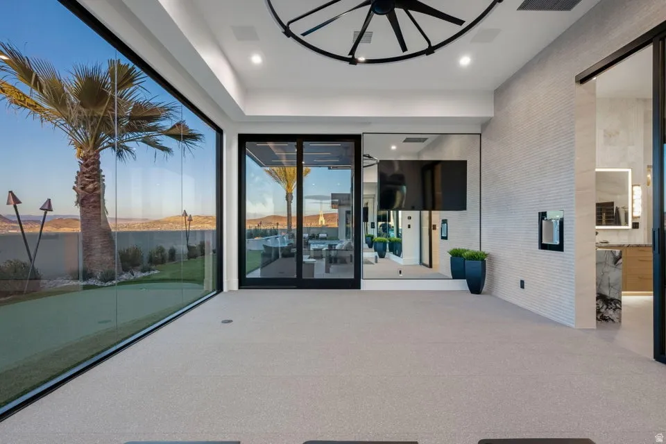 Expansive floor-to-ceiling glass wall, light gray carpet flooring, recessed lighting, and a modern ceiling fixture