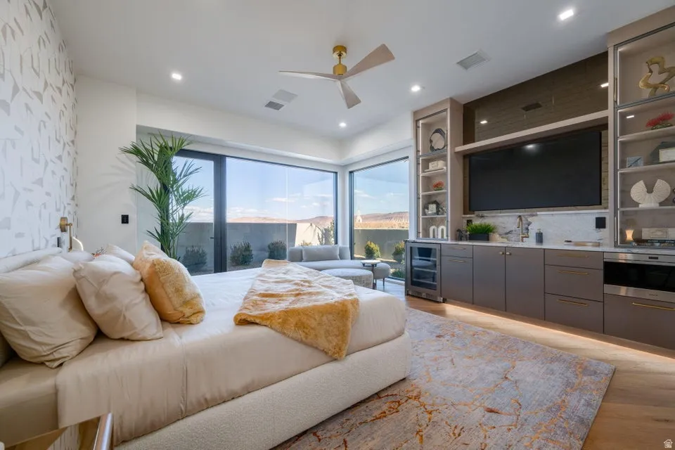 Spacious bedroom featuring large format floor-to-ceiling windows, wood-finish flooring, and a built-in media center with shelving