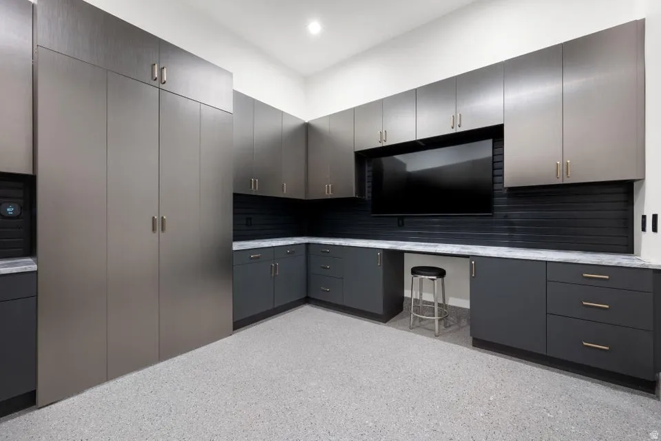 Custom storage system featuring extensive cabinetry, integrated workspace, durable epoxy flooring, and full-height built-in units