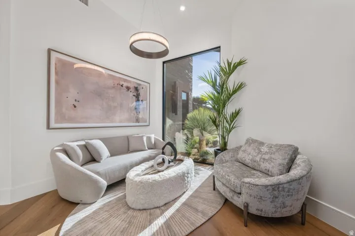 Bright interior space featuring a floor-to-ceiling window, wood-finish flooring, and a contemporary circular pendant light fixture