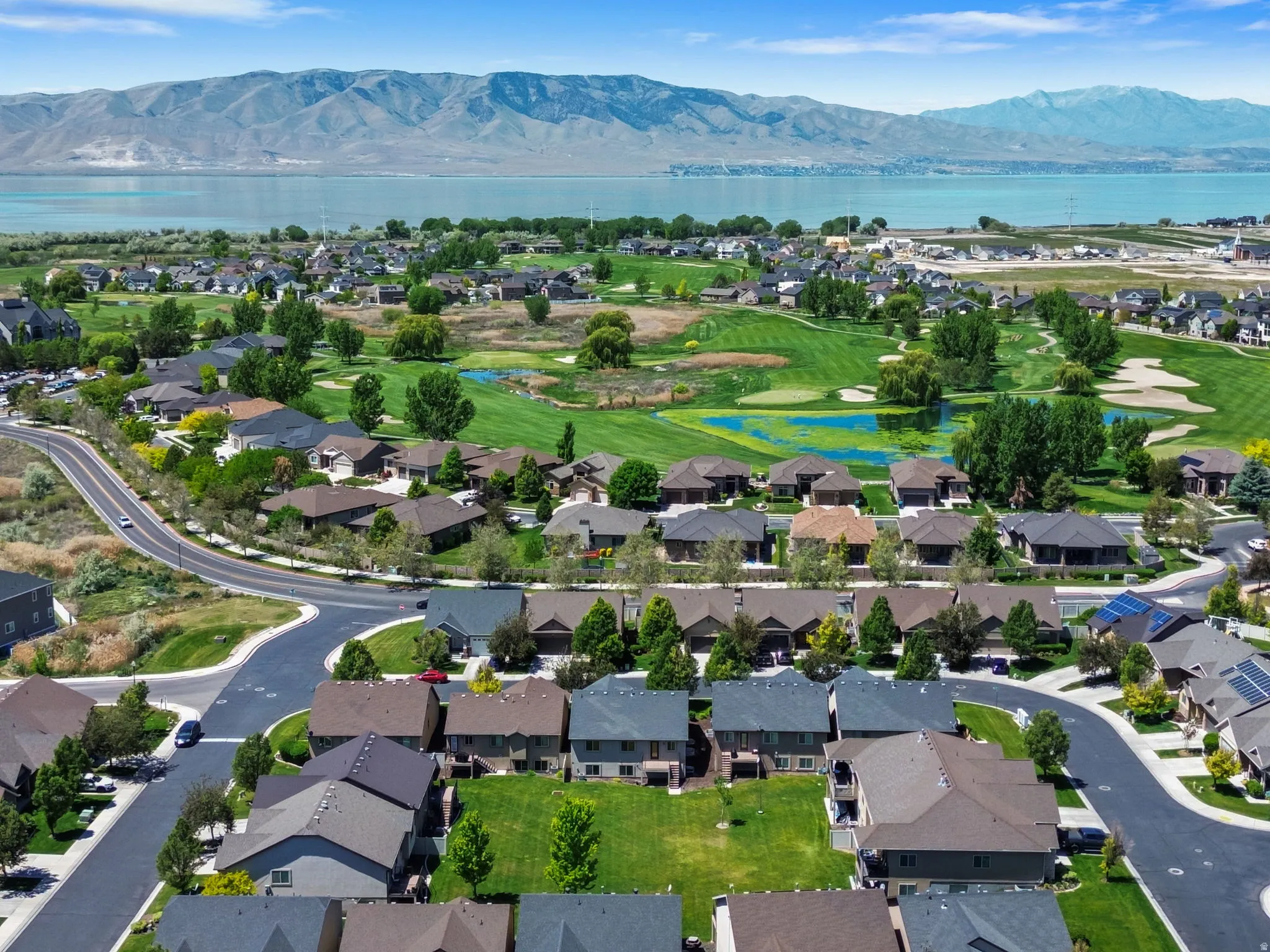 Expansive aerial view showcasing a residential community with a large body of water and mountains in the background