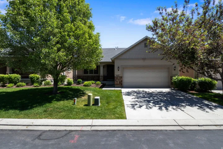 Single-story property featuring a two-car garage, concrete driveway, and mature landscaping