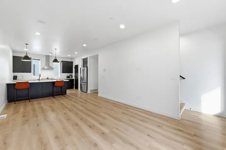 Open-concept living space with light wood-finish flooring, recessed lighting, and a contemporary kitchen