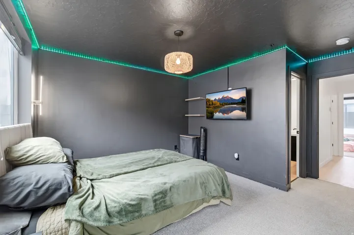 Interior room featuring dark gray walls and ceiling, carpet flooring, a wall-mounted television, and recessed ceiling lighting