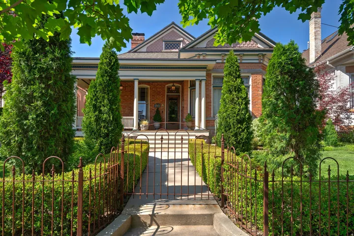 Brick exterior with a covered porch featuring columns and a detailed railing