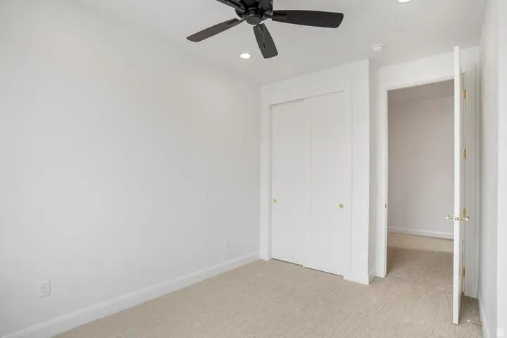 Room featuring neutral-toned carpeting, white walls, and a ceiling fan with integrated lighting