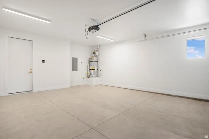 Spacious garage featuring a concrete floor, bright overhead lighting, and white painted walls