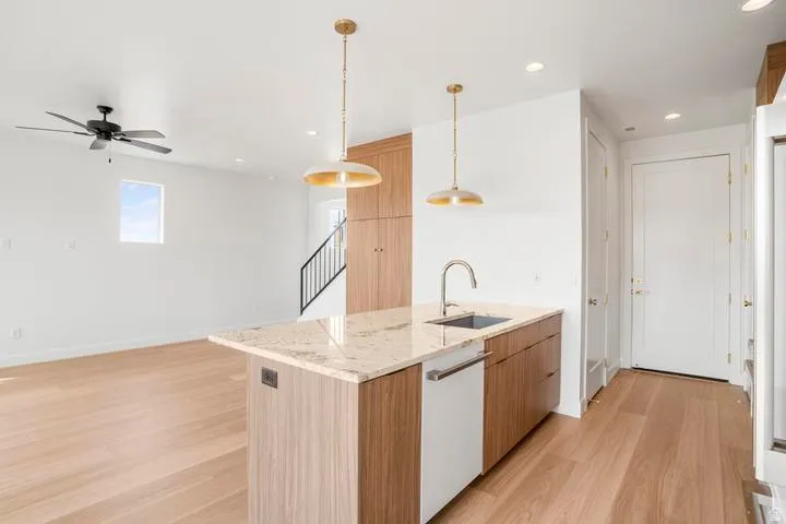 Kitchen island with a light-toned countertop, integrated sink, and dishwasher