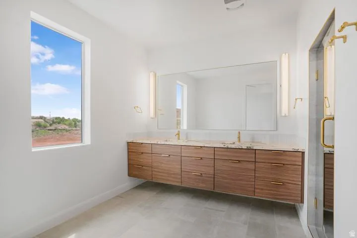 Floating wood-finish vanity with dual sinks, stone countertop, and full-width mirror