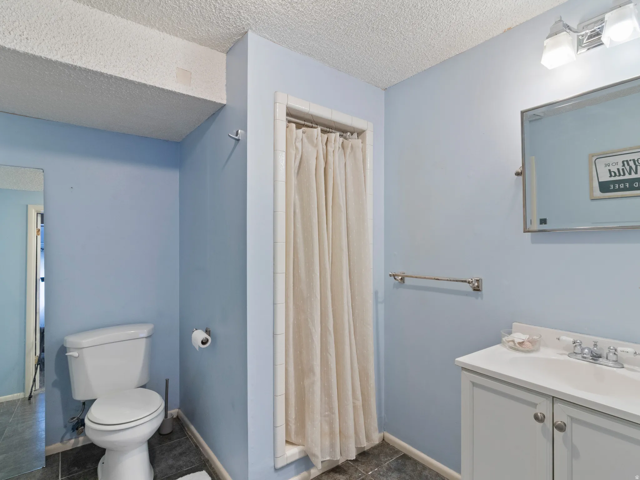 3/4 Bathroom featuring a white vanity with integrated sink, chrome hardware, and wall-mounted mirror with overhead lighting