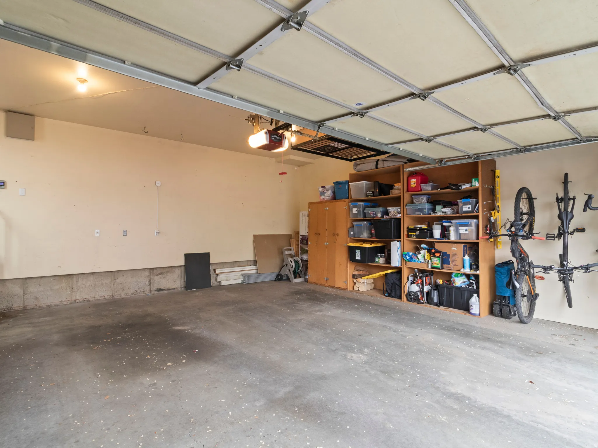 Oversized Spacious garage featuring a concrete floor, overhead garage door with opener, and built-in wood shelving for storage