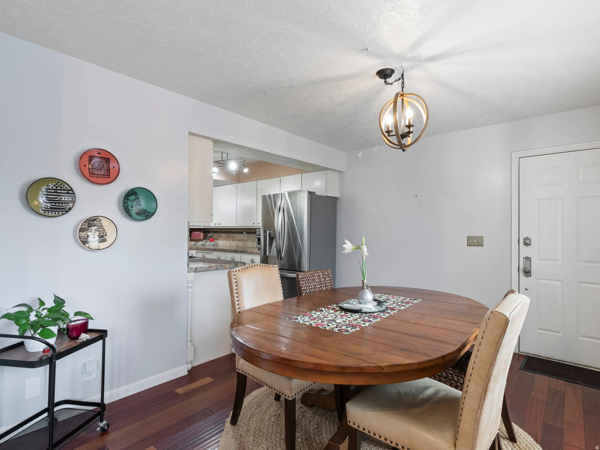Dining area featuring wood-finish flooring, a contemporary orb chandelier, and an open pass-through to the kitchen