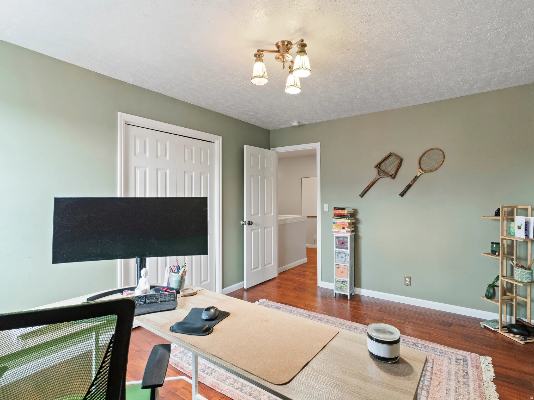 Interior room featuring wood-finish flooring, light green walls, a white paneled door. Great space for a home office