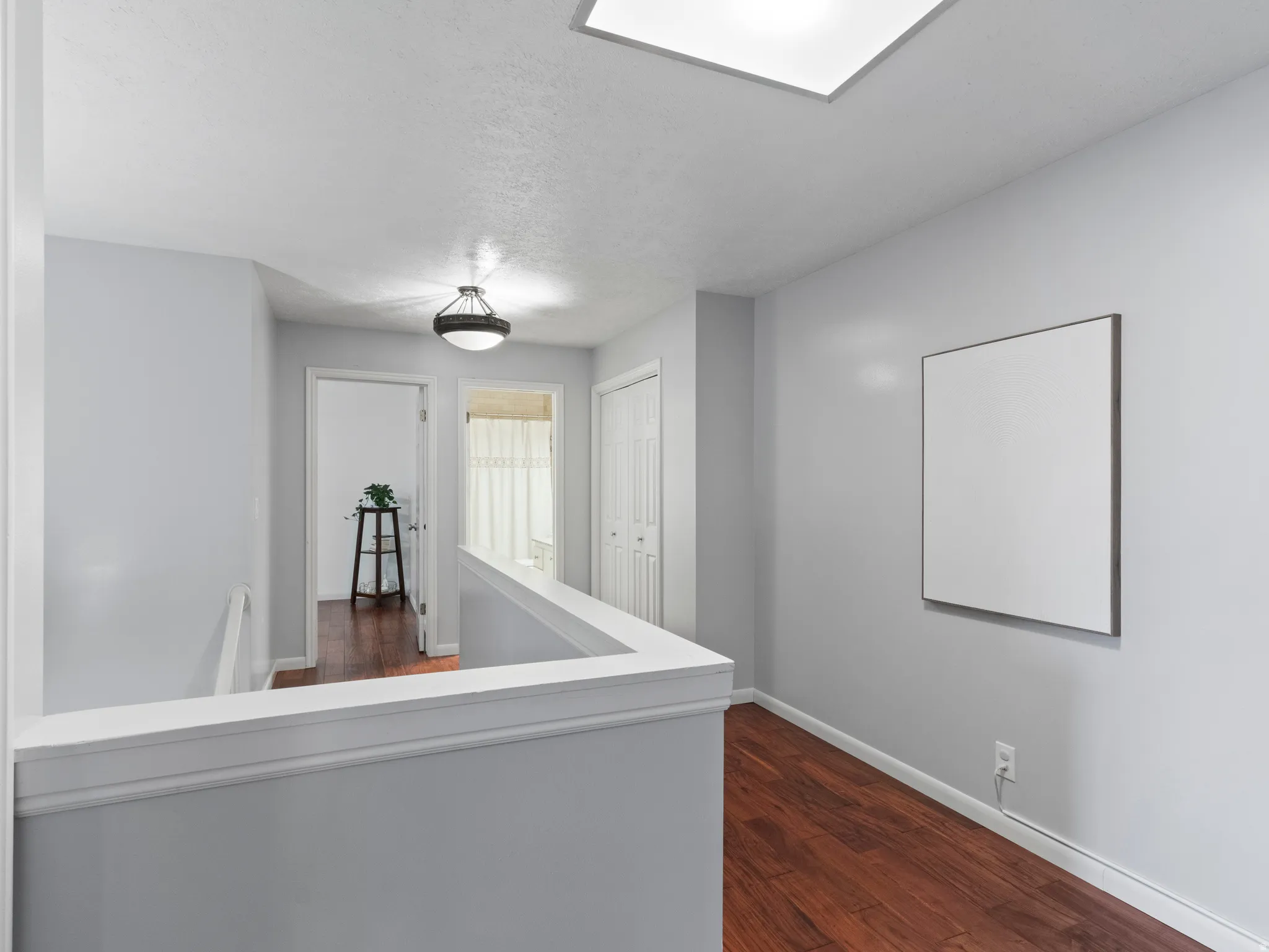 Upper-level hallway featuring wood-finish flooring and light gray walls