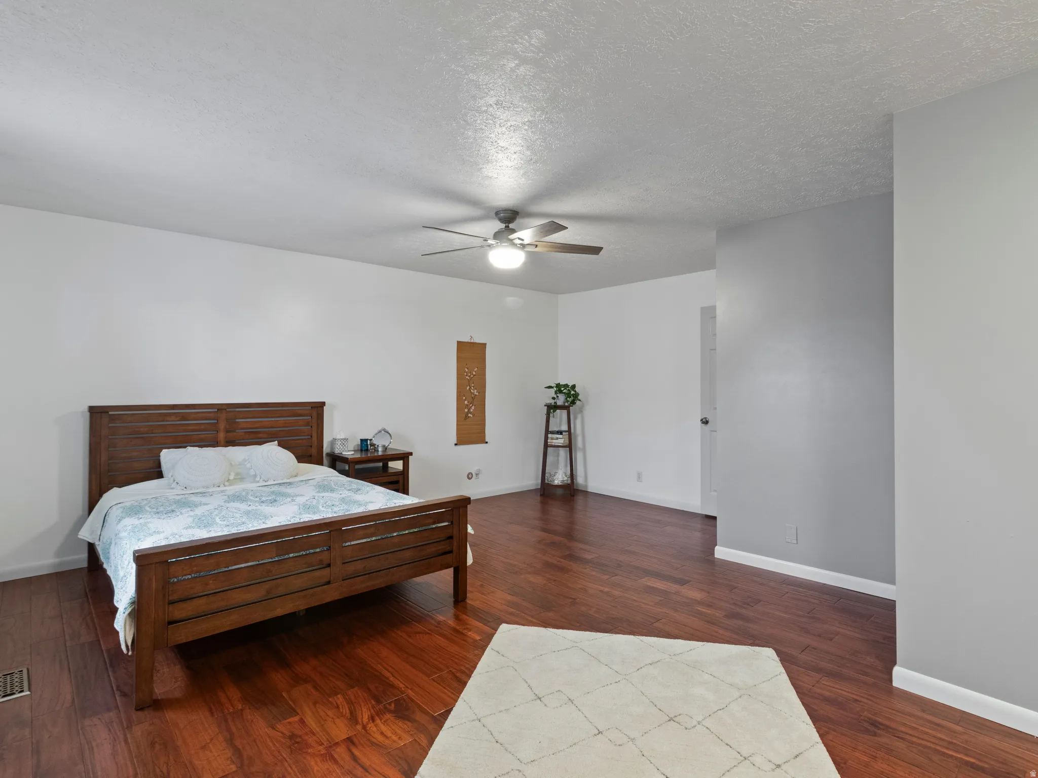 Spacious room featuring wood-finish flooring, a contemporary ceiling fan, white baseboards, and neutral wall paint
