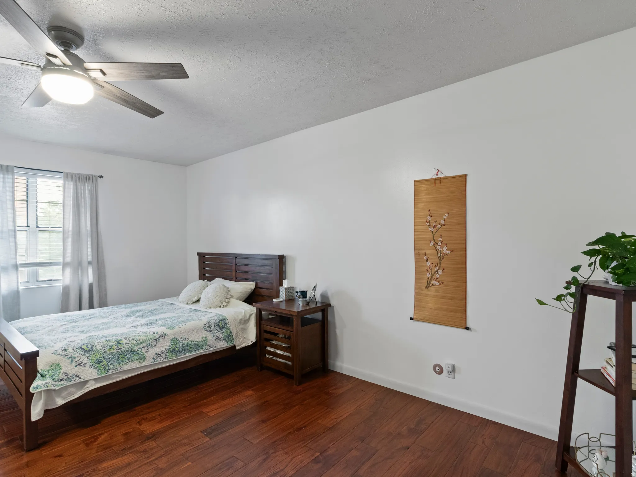 Interior room featuring rich wood-finish flooring, white walls, and a ceiling fan with integrated lighting