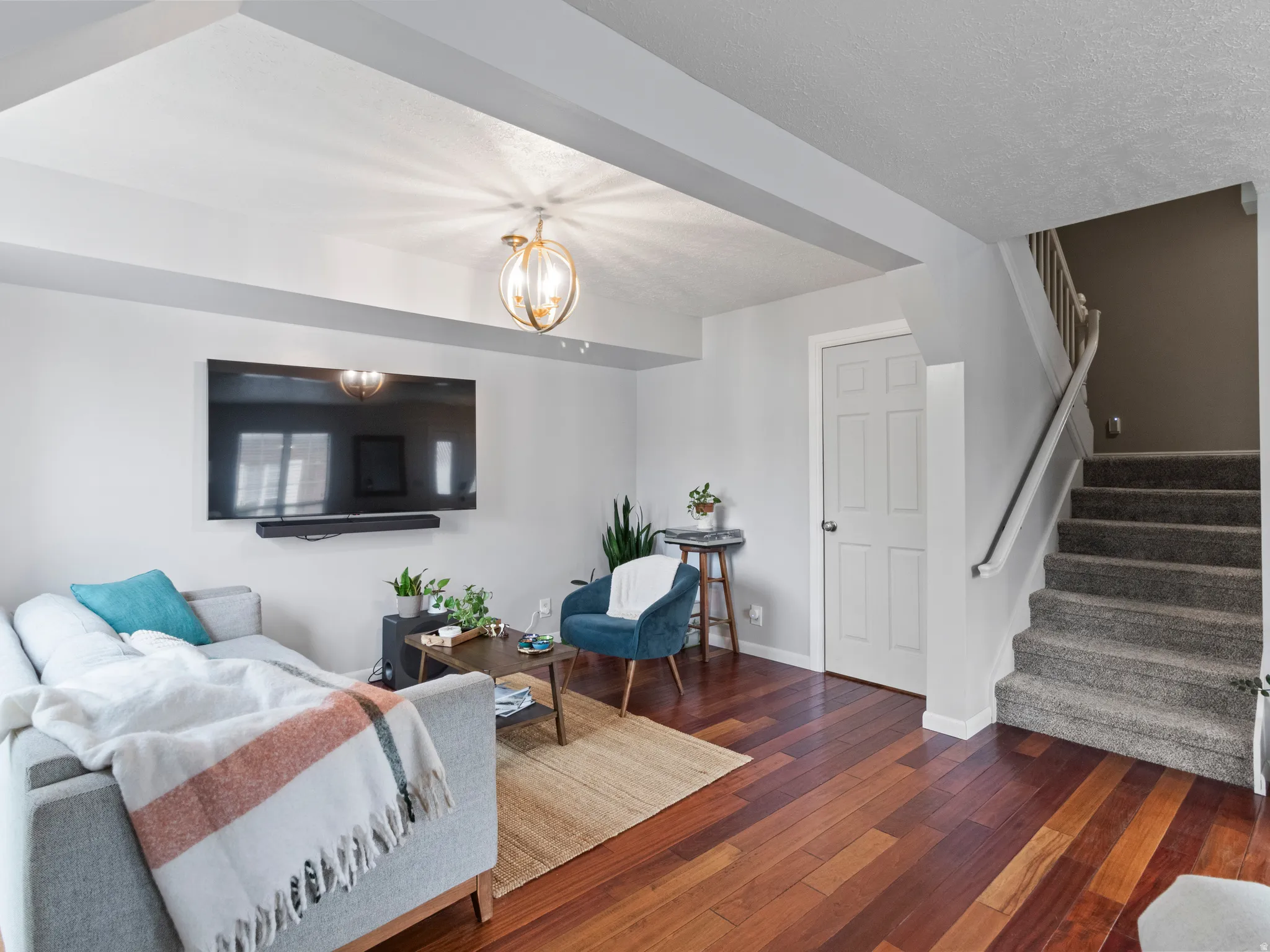 Hardwood-finish flooring anchors this living space, featuring a staircase to the second floor