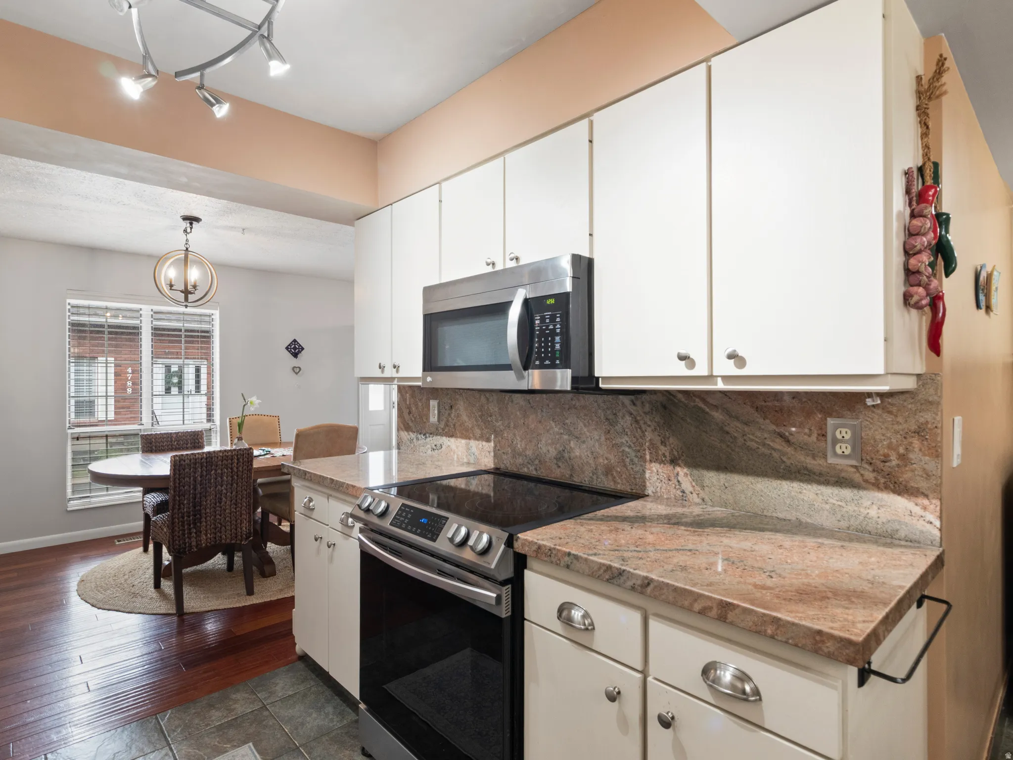 Kitchen featuring white cabinetry, stainless steel appliances, Granite countertops, and a matching  backsplash
