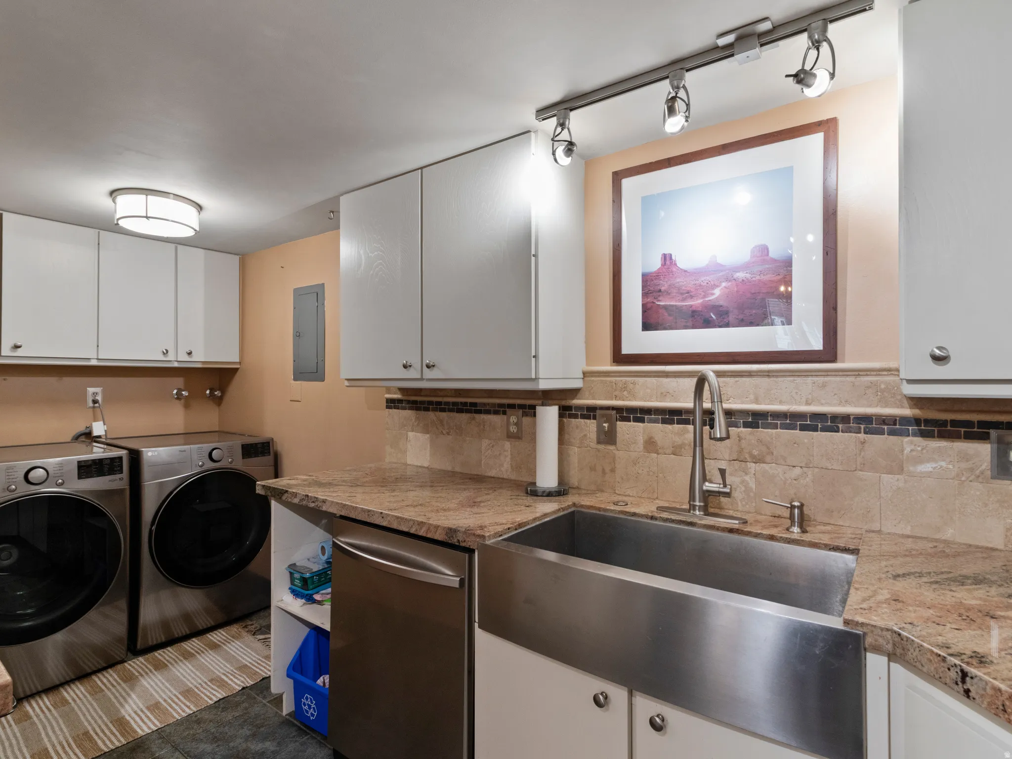 Functional utility space featuring a stainless steel apron front sink, granite countertops, and a tiled backsplash