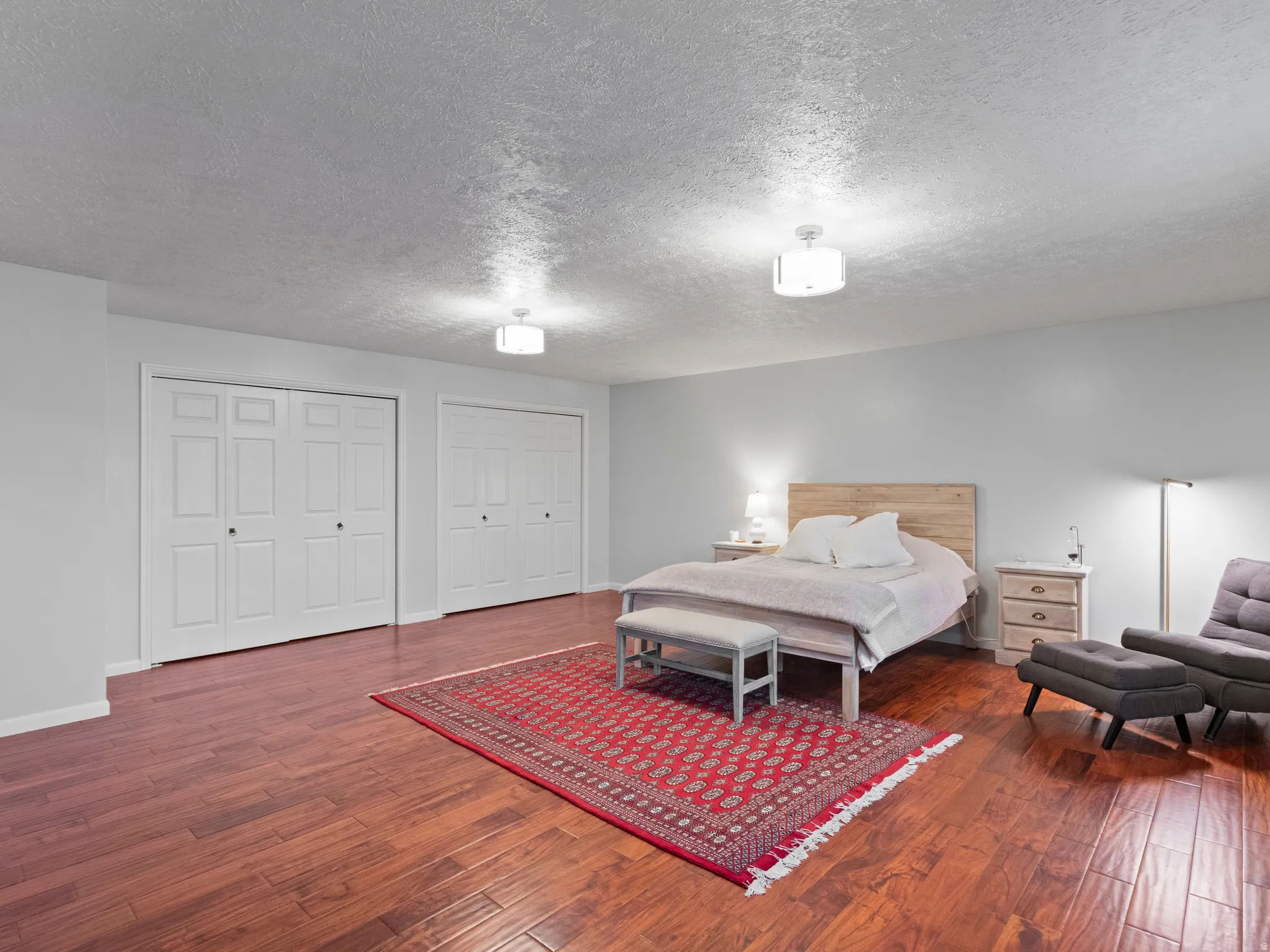 Spacious master bedroom featuring rich wood-finish flooring. Double closets
