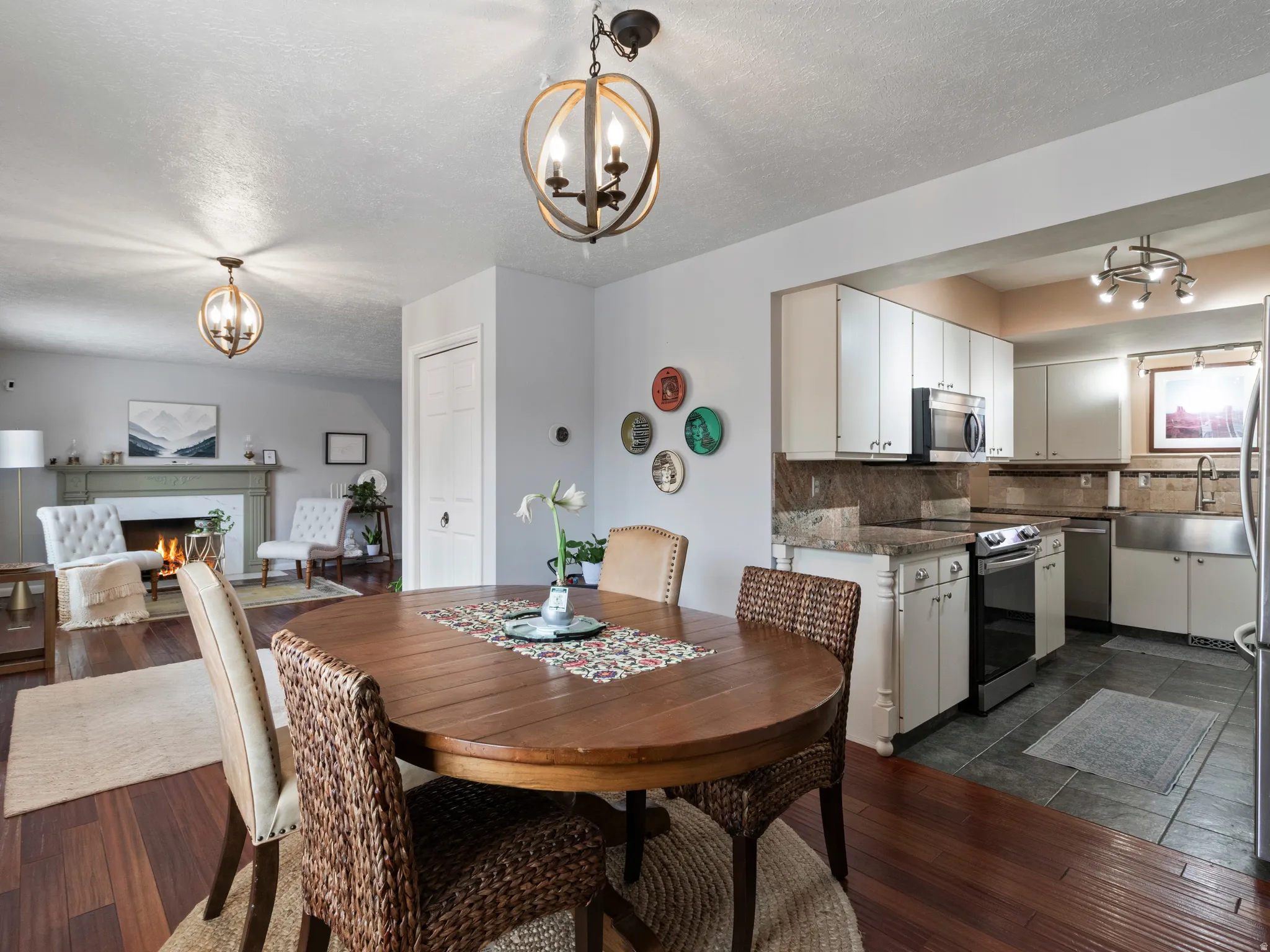 Open-concept dining area featuring wood-finish flooring, a contemporary chandelier, and a pass-through opening to the kitchen